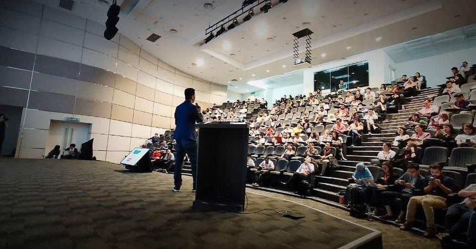 An Azend speaker on stage addressing a full lecture theatre