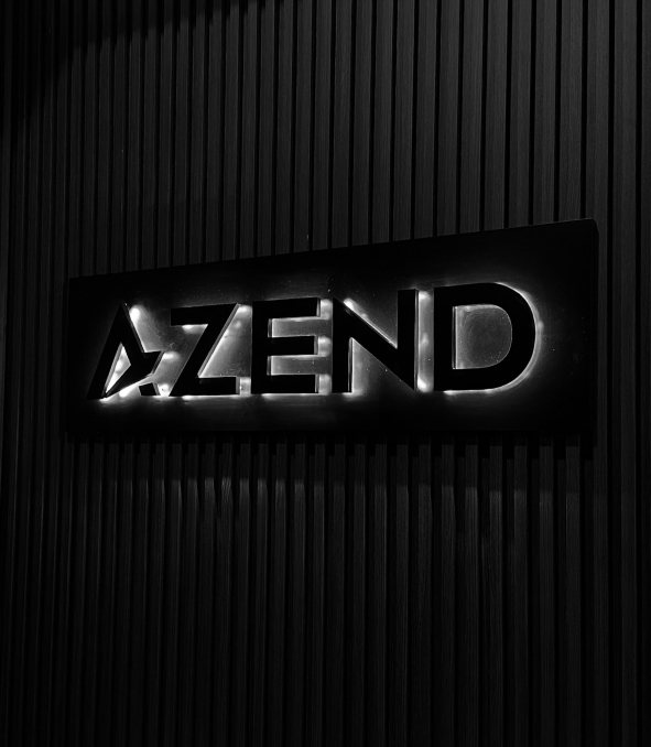 The illuminated Azend logo sign on a slatted wall