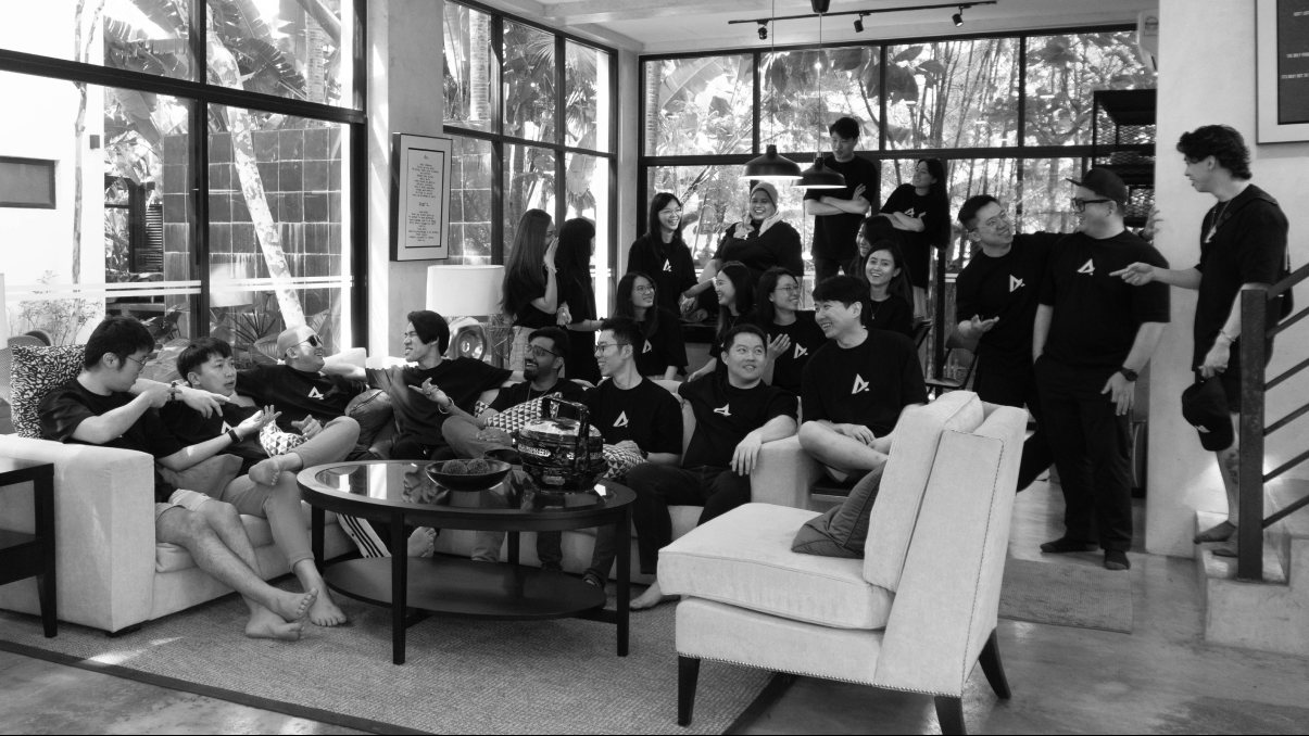 The Azend team together in matching black Azend T-shirts in a bright, plant-filled office lounge
